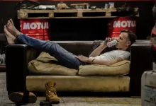 a man laying on a couch drinking from a bottle
