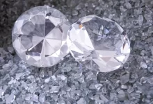 two diamonds sitting on top of a pile of crushed glass