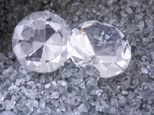 two diamonds sitting on top of a pile of crushed glass