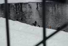 person in black jacket and black pants sitting on snow covered ground during daytime