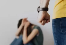 Man Clenching Fist Near a Woman Covering Face While Sitting