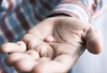 person holding pink round medication pill