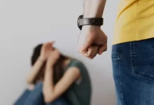 Man Clenching Fist Near a Woman Covering Face While Sitting