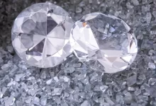 two diamonds sitting on top of a pile of crushed glass