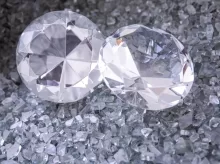 two diamonds sitting on top of a pile of crushed glass