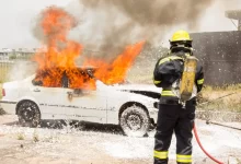 firefighter fighting burning car