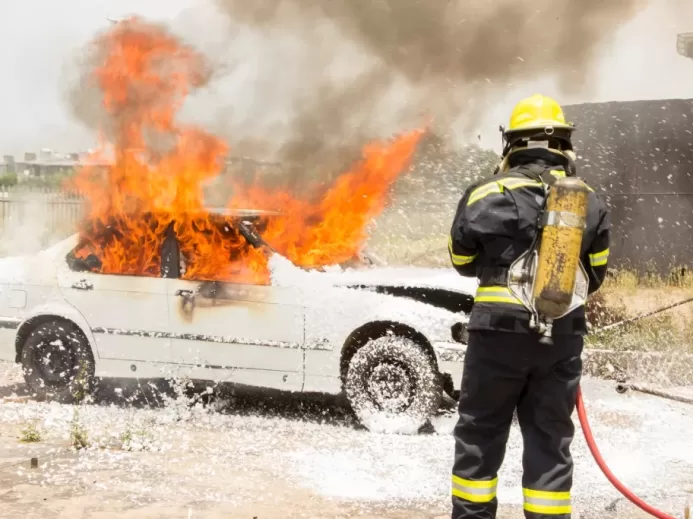 firefighter fighting burning car