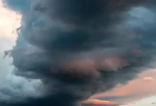 a large cloud is in the sky over a field