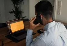 man in blue dress shirt holding black smartphone