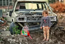 Girl with Backpack near Broken Car Ruins