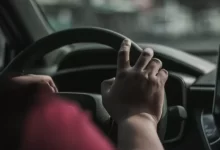 a person driving a car with their hand on the steering wheel