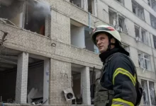 Firefighter in front of a Residential Building Destroyed by Shelling