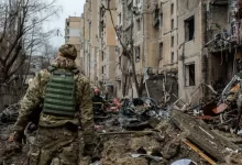 a man in camouflage walking through a destroyed building