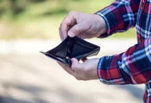 person in red blue and white plaid long sleeve shirt holding black leather bifold wallet