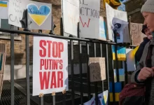 a woman standing in front of a fence with signs on it