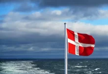 us a flag on flag pole near sea under cloudy sky during daytime