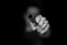 grayscale photography ofperson holding gun