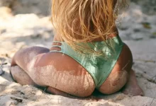 woman wearing green bikini bottom sitting on sand
