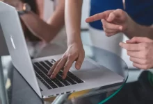 person touching and pointing MacBook Pro