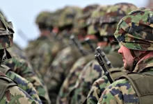 man in green and brown camouflage uniform holding black rifle