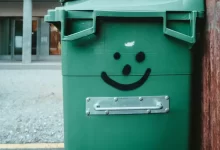 green trash bin on sidewalk