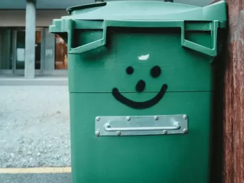 green trash bin on sidewalk