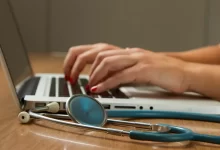 person sitting while using laptop computer and green stethoscope near