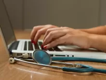 person sitting while using laptop computer and green stethoscope near
