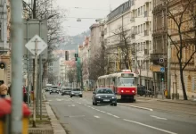 a red and white bus driving down a street next to tall buildings
