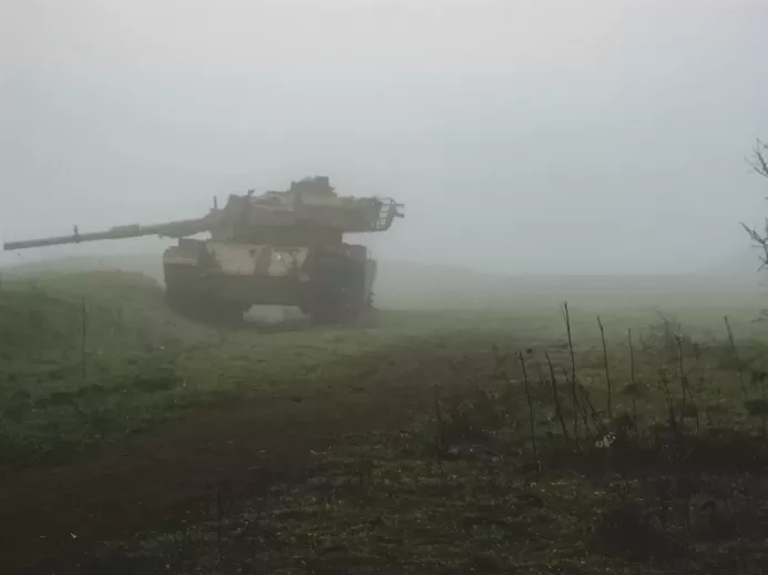 a tank driving through a foggy field