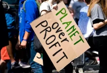 woman holding Planet over Profit placard