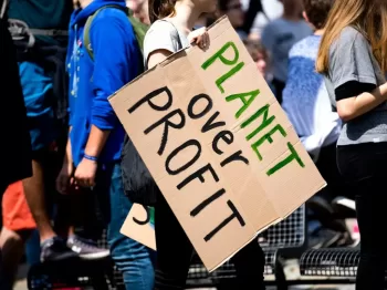 woman holding Planet over Profit placard