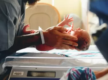 person wearing gray shirt putting baby on scale