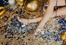 Elegant legs amidst a colorful mix of confetti and balloons, capturing a vibrant celebration aftermath.
