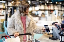 Žena s mobilním telefonem v supermarketu