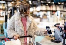 Žena s mobilním telefonem v supermarketu