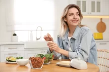 Žena u stolu, na kterém jsou mandle a salát.