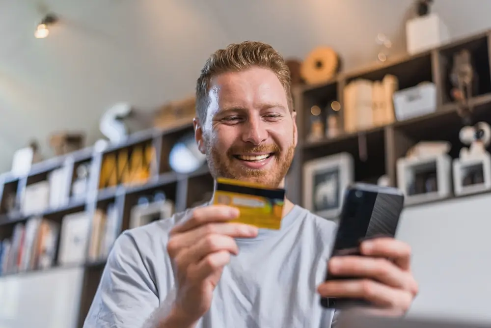 shutterstock_2139590189 1 - Pravda24 Muž, který drží v ruce mobilní telefon a platební kartu.
