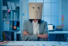 Žena se sáčkem, kde je nakreslený mračící se obličej, na hlavě.
