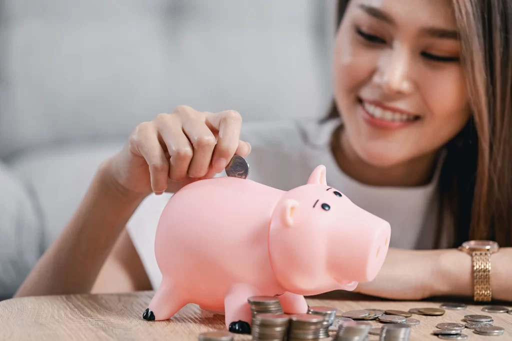 Čím dříve spořit začnete, tím lépe. Zdroj: Shutterstock - Pravda24 Žena házející peníze do prasátka.