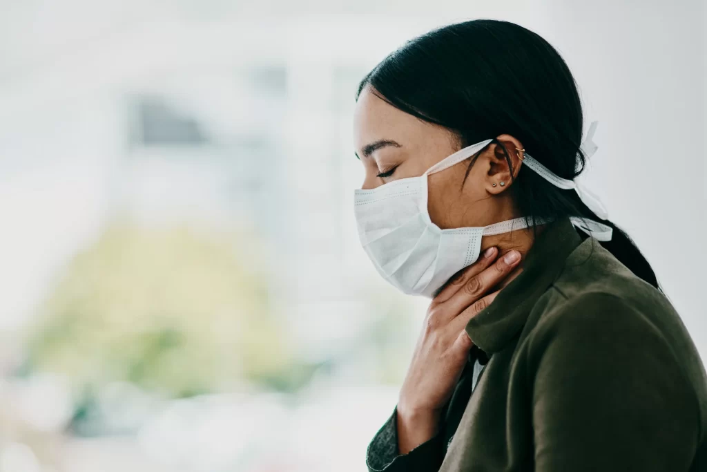 Jste-li nemocní, do společnosti choďte pouze s rouškou. Zdroj: Shutterstock - Pravda24 Žena, kterou bolí v krku a má roušku.