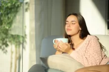 Žena sedí na gauči a pije čaj.