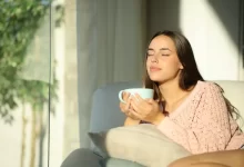 Žena sedí na gauči a pije čaj.