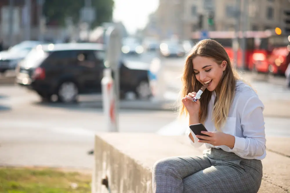 shutterstock_1392795131 - Pravda24 Žena sedí, dívá se do mobilu a jí sladkou tyčinku.