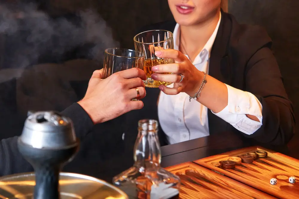 shutterstock_1564189435 - Pravda24 Žena drží v ruce sklenici s alkoholem a přiťukává si s mužem.