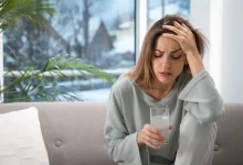 Žena sedí a drží se za hlavu.