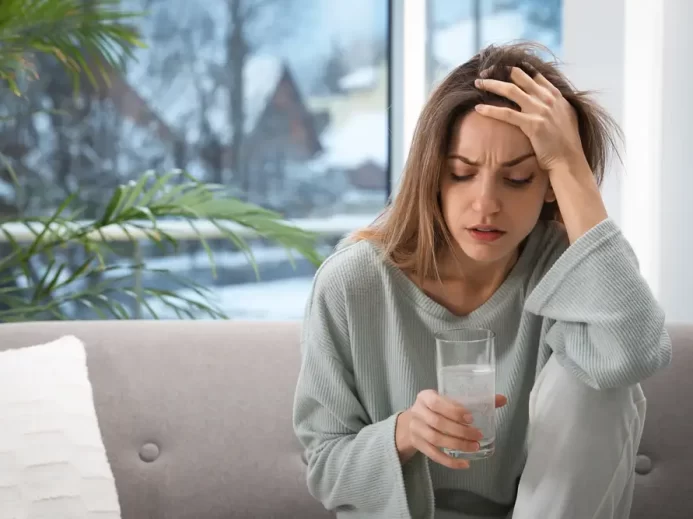 Žena sedí a drží se za hlavu.