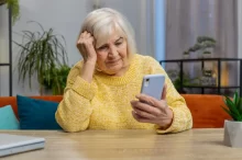 stará žena si čte zprávu na telefonu