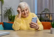 stará žena si čte zprávu na telefonu