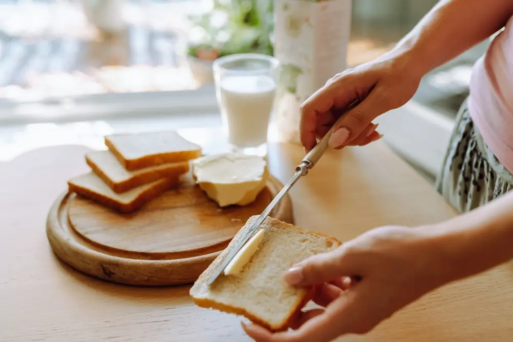 shutterstock_2504940865 - Pravda24 Žena si maže máslo na toast.